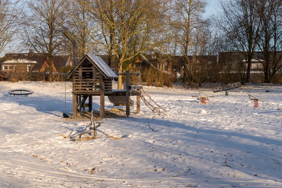 Snieguota vaikų žaidimų aikštelė po giedru žiemos dangumi